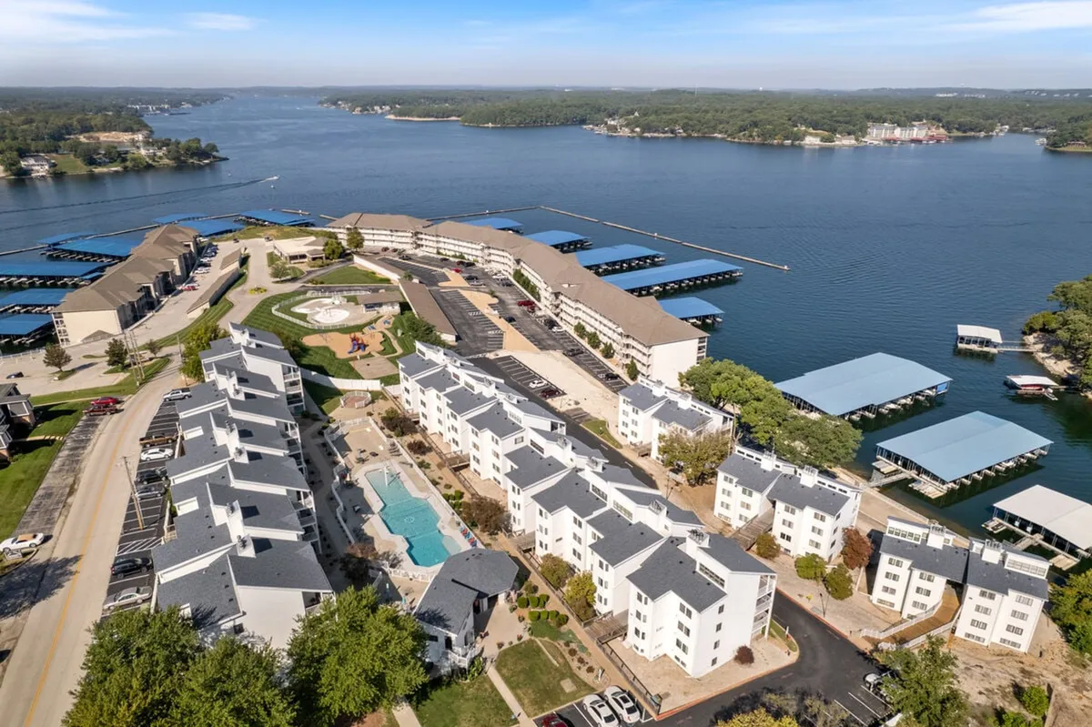 This exterior scene showcases a vibrant waterfront area that includes a swimming pool, landscaped gardens, and boathouses, with people enjoying activities like swimming, boating, picnicking, and walking. The lively atmosphere and diverse activity options are visible, reinforcing the section's focus on family-friendly lake adventures and group fun.