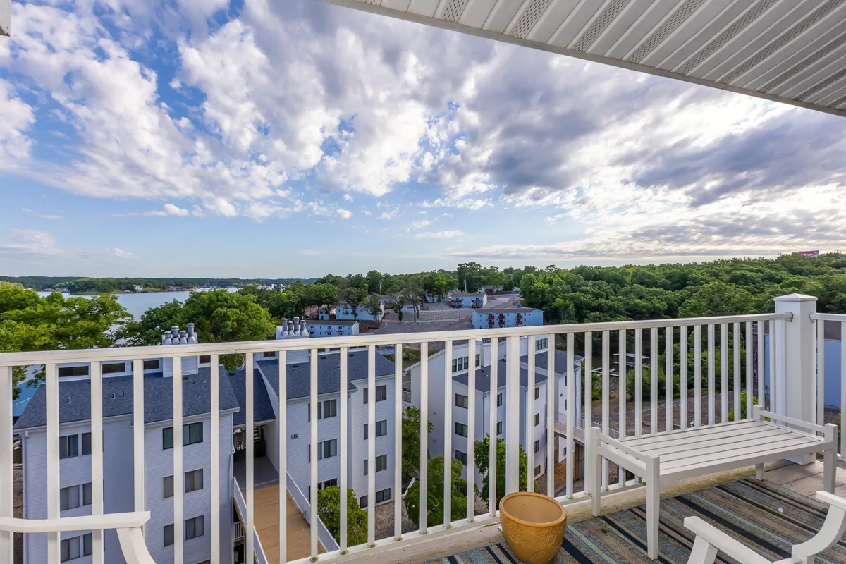 A tranquil view from the balcony, complete with railing, overlooking the lake, clouds, and surrounding greenery. The scene invites moments of calm—perfect for a morning coffee or an evening gathering, connecting the interior with the natural beauty outside.