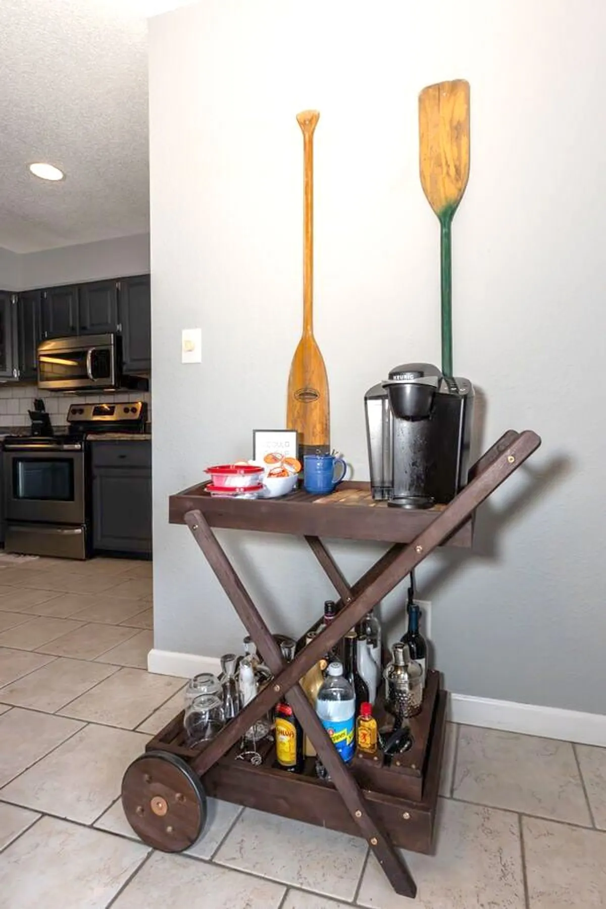 A stylish drinks and coffee station featuring a wooden paddle, a green paddle, a coffee maker, and a cocktail cart. The setup invites guests to enjoy morning coffee or evening drinks, reflecting thoughtful hospitality and local charm.
