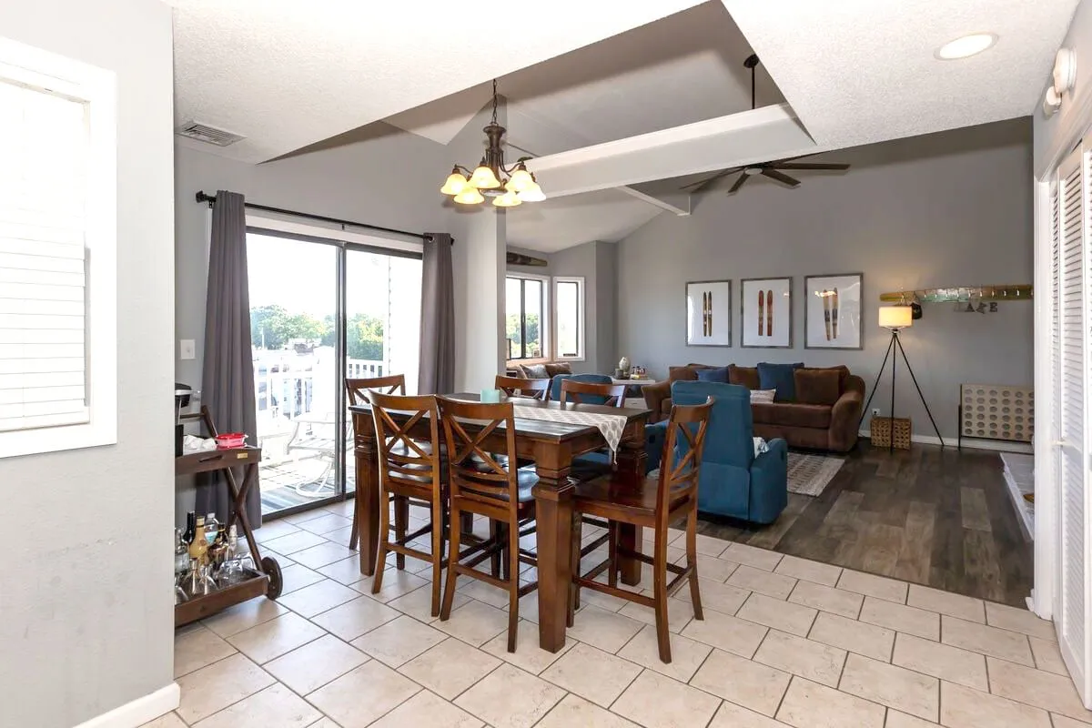 An integrated space featuring a dining table and a cozy living room seating area, all framed by large windows looking out onto serene views. The atmosphere is relaxed and perfect for both social gatherings and quiet moments.