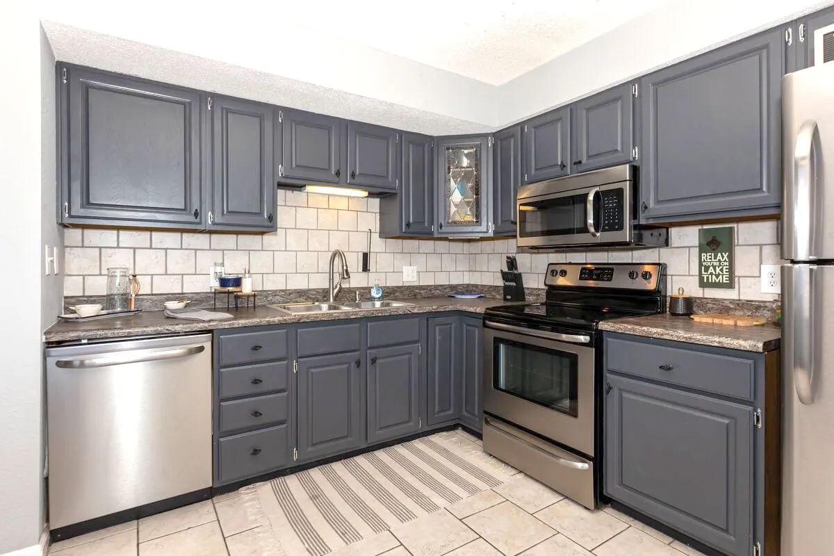 This image shows a modern kitchen featuring stainless steel appliances, a granite countertop, and sleek cabinetry, with decorative wall art adding a touch of warmth. The setup is inviting and functional, perfect for cooking, entertaining, or gathering as a family.