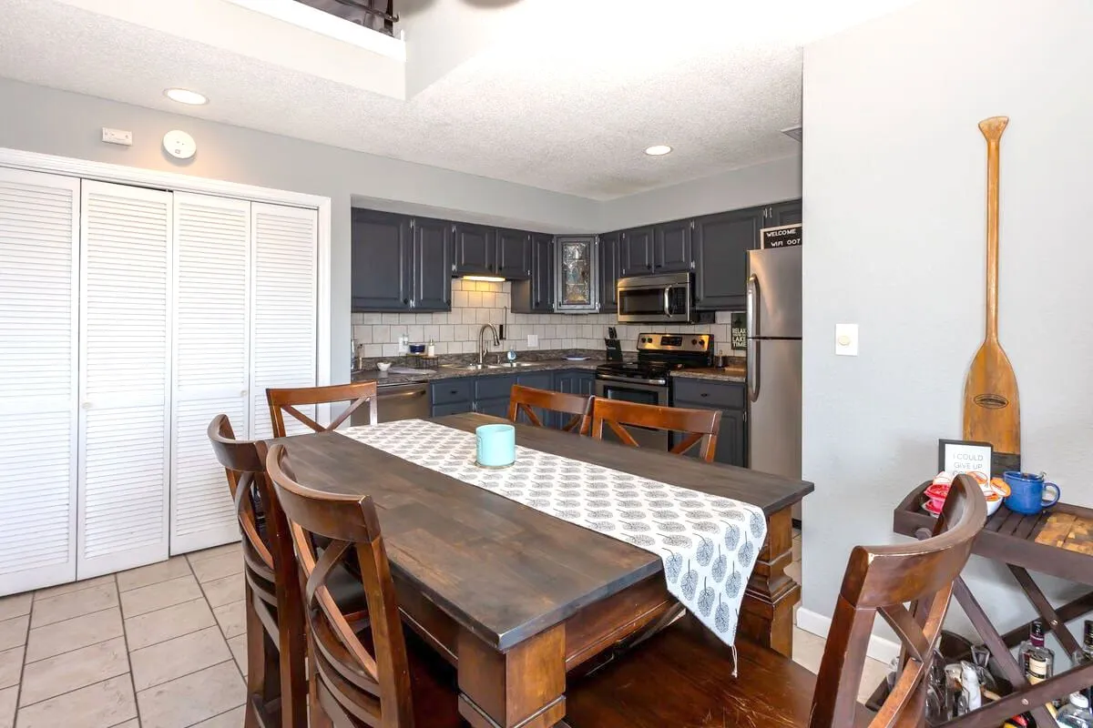 A cozy view of the dining table and kitchen counter, surrounded by appliances and decorative touches, suggesting a space designed for intimate family dinners, social gatherings, and creative cooking projects.