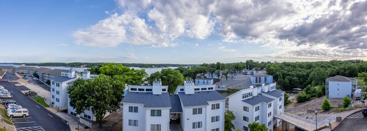 A tranquil view over the lake framed by green trees and modern architecture. The image hints at boating, picnicking, and walking trails, while offering a peaceful sunset backdrop that invites families to explore the natural beauty of the area together.