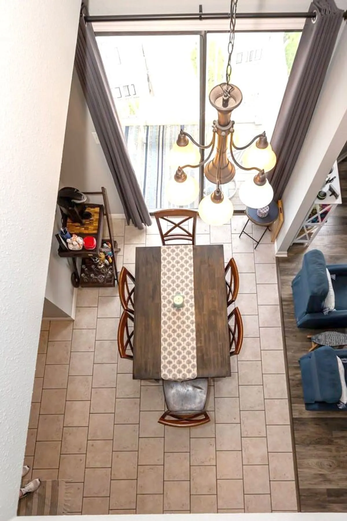 A welcoming dining space with a large table, chandelier, views through the window, a cozy seating area, and a stylish bar cart. Natural light streams in, and the scene suggests both everyday family meals and festive gatherings.